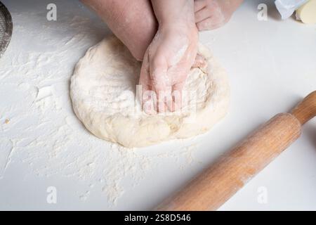 The hands of a man and a child in flour make a pie or pizza from dough. The concept of family relationships, support and love. Spending time together Stock Photo