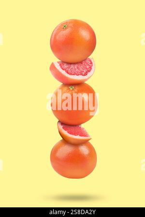 Fresh grapefruits in air on light yellow background Stock Photo