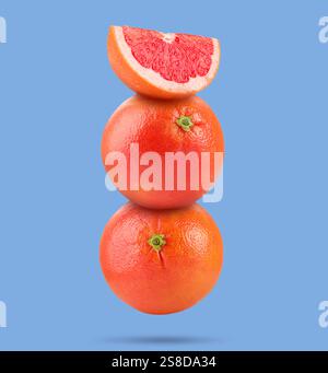 Fresh grapefruits in air on light blue background Stock Photo
