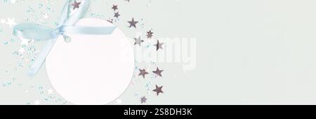 Banner with silver tag with tied ribbon bow. Stars confetti scattered on a blue background. Stock Photo