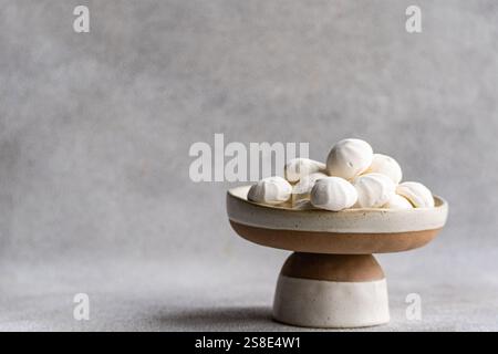 A charming arrangement of homemade mini zephyr marshmallows displayed on a two-tone ceramic pedestal dish, creating an elegant and inviting minimalist Stock Photo