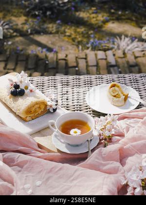 A delectable Swiss roll filled with rich dulce de leche, presented on a garden table, accompanied by tea and spring blossoms. Stock Photo