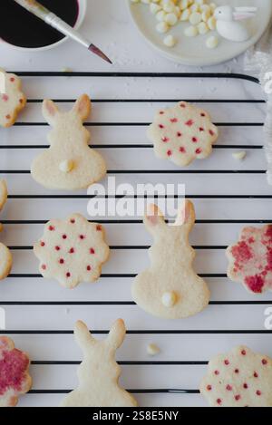 Top view of Easter bunny-shaped cookies delicately painted with hibiscus tea on a cooling rack. The image captures the intricate details of the natura Stock Photo