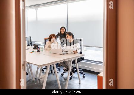 Three coworkers engage in a collaborative teamwork session, discussing ideas in a modern office with natural light The atmosphere reflects creativity Stock Photo