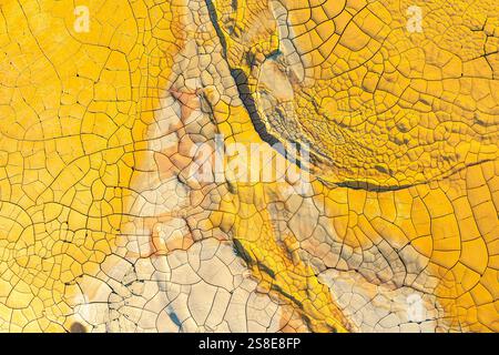 Vibrant, high-resolution image showcasing the intricate patterns and deep cracks of dried, golden mud. Ideal for backdrop or texture use. Stock Photo