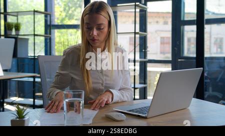 Caucasian business girl manager analyst professional accountant office employee working on laptop computer writing notes financial papers documents Stock Photo