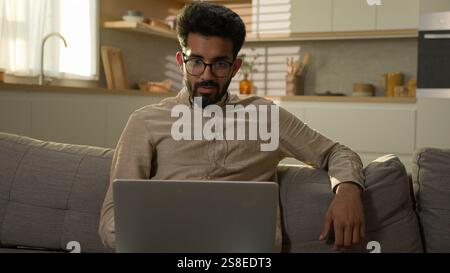 Arabian muslim man freelancer working from home focused millennial guy indian businessman typing on computer laptop surfing internet looking at screen Stock Photo