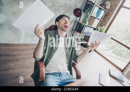 Young man celebrating success in modern office workspace with a joyful expression Stock Photo