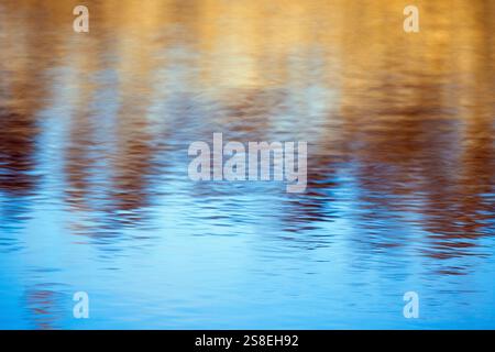 Abstract natural blurred background photography, rippled water surface with colorful reflections of an autumn forest on a sunny day Stock Photo