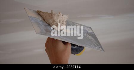 man plastering ceiling repair. Selective focus. Stock Photo