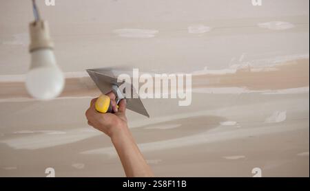 man plastering ceiling repair. Selective focus. Stock Photo