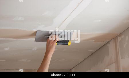 man plastering ceiling repair. Selective focus. Stock Photo