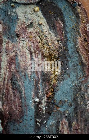 Close-up view of a textured surface featuring worn paint in earthy colors. The layering of dirt and paint creates a unique abstract pattern Stock Photo