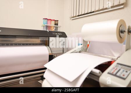 Wide-format printer and roll laminator with paper indoors, selective focus. Printing house Stock Photo