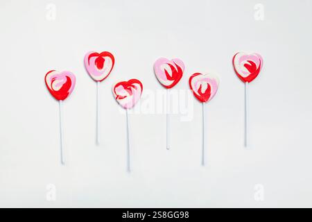 Heart-shaped lollipops arranged on a white background for festive celebration, Valentine's day treat Stock Photo