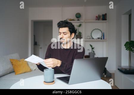 Young stressed looking handsome middle eastern man using computer and being overwhelmed by work. Stock Photo