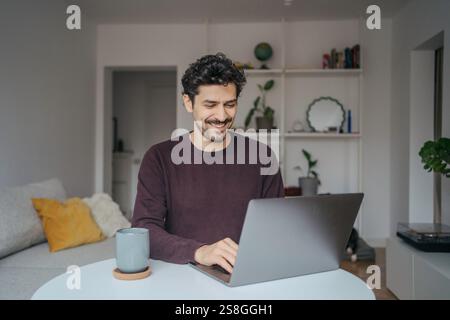 Young handsome middle eastern looking man using laptop computer in his home. Stock Photo