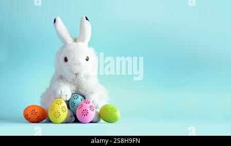 Easter bunny with colorful easter eggs on a blue background. Stock Photo