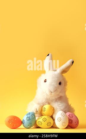 Easter bunny with colorful easter eggs on a yellow background. Stock Photo