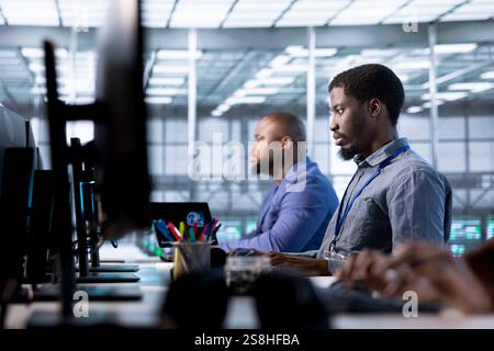 Team of admins in data center using diagnostic tools and system monitoring software on computers to identify root cause of errors. Teamworking IT professionals in server farm repairing infrastructure Stock Photo