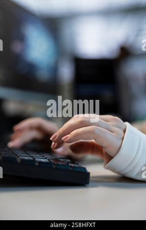 Engineer typing on keyboard in data center coordinating deployment of server architecture, improving data processing speed. Close up of employee in server farm configuring and testing hardware Stock Photo