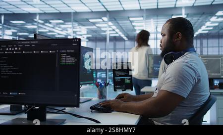 Portrait of joyful technician working in high tech workplace providing computing resources for different workloads. Radiant IT specialist tasked with monitoring data center mainframes, camera B Stock Photo
