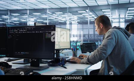 Technician arriving at work in high tech server room, analyzing data on monitors, ensuring seamless data flow. Man starting job shift in data center, ensuring system integrity and security, camera B Stock Photo