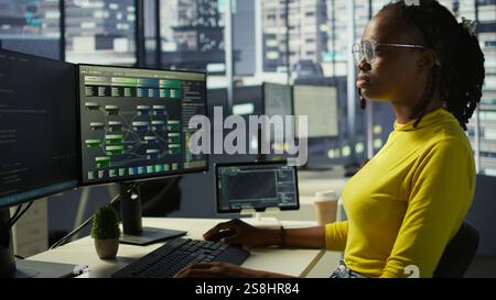 Portrait of smiling computer scientist at work doing software debugging using PC, checking glitches in lines of code. Cheerful IT specialist in office fixing coding issues using computer, camera B Stock Photo