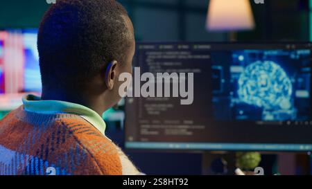 African american man working on computer to write code and programming in artificial intelligence and deep learning. Male IT engineer using pc to ensure cyber security, neural network. Camera A. Stock Photo
