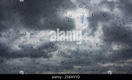 Focus on raindrops on window pane with storm clouds defocused beyond Stock Photo