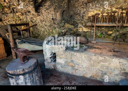 Krka National Park, Šibenik-Knin - HR - Oct 17, 2024 A traditional blacksmith workshop with an anvil on a wooden stump, stone forge, tools, and rustic Stock Photo