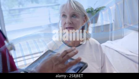 Image of dna strand rotating over diverse male doctor with tablet and senior female patient Stock Photo
