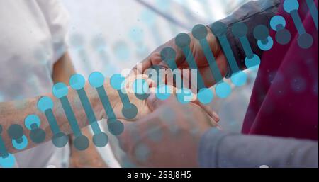 Image of dna strand rotating over diverse male doctor massaging hand of senior female patient Stock Photo