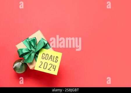 Sticky note with goals for 2024 and gift box on red background Stock Photo