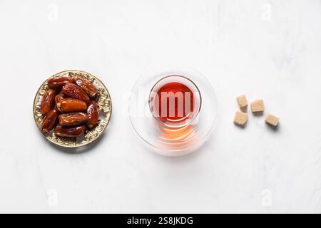 Glass of Turkish tea with sugar cubes and dried dates on white background Stock Photo