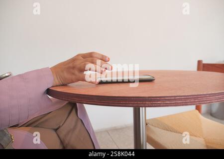 A hand grabbing and picking up mobile phone on the table. Stock Photo