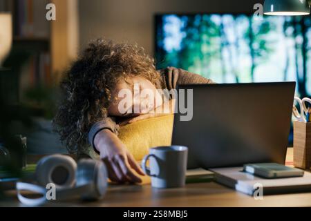 Woman working late at night in her home office, she fell asleep in front of the laptop: burnout, deadlines and insomnia concept Stock Photo
