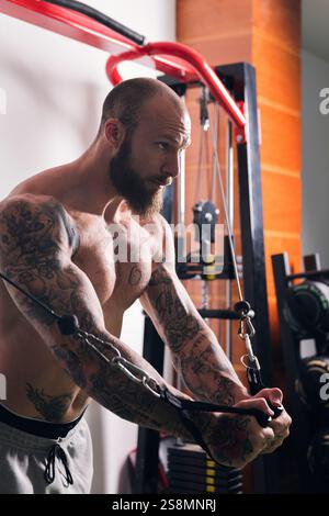 concentrated muscular man doing exercise at gym Stock Photo