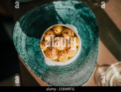 A plate of food with a blue bowl on top. The bowl is filled with yellow food. The plate is on a table Stock Photo