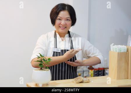 A deaf person is employed as a staff at coffee shop, pin a deaf staff sign on apron, using sign language to communicate with customers to take orders Stock Photo