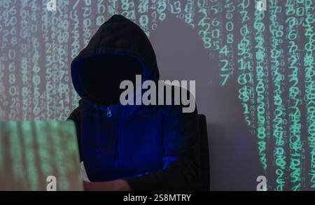 Dangerous hooded hacker breaks into data servers and infects their system with a virus. Selective focus. Stock Photo