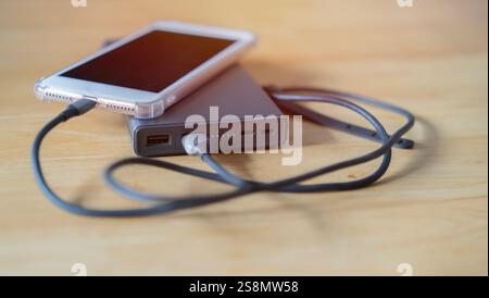 Selective focus of white smartphone and power bank on wooden background. Charging concept. Stock Photo