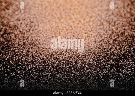 Gradient of Sparkling Textures,  a gradient texture transitioning from deep black tones at the bottom to warm, light browns and golden hues at the top Stock Photo