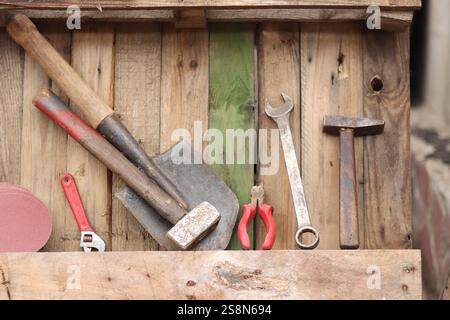 Old hand tools on a background of wooden boards nailed together. Background of old boards and tools laid out in a row. Old tool. Sledgehammer, hammer, Stock Photo