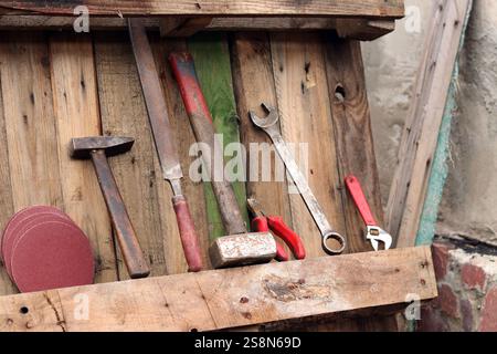 Old hand tools on a background of wooden boards nailed together. Background of old boards and tools laid out in a row. Old tool. Sledgehammer, hammer, Stock Photo