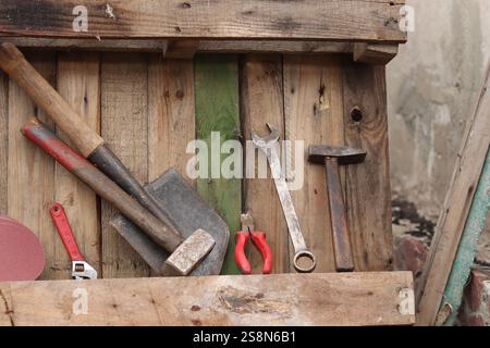 Old hand tools on a background of wooden boards nailed together. Background of old boards and tools laid out in a row. Old tool. Sledgehammer, hammer, Stock Photo