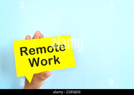 Human hand holding yellow speech bubble with written phrase Remote Work. Hiring for remote work setup. Stock Photo