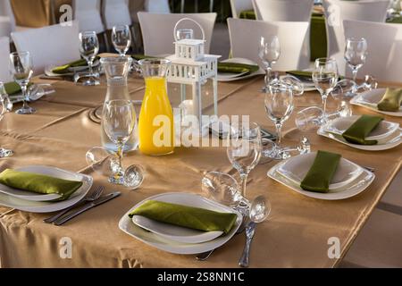 Elegantly set table with wine and water crystal, cutlery and napkins on a pressed cloth at a wedding banquet. Stock Photo