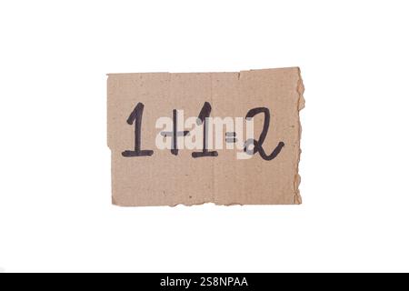 1+1=2 handwritten on a piece of +cardboard on a white background with copy space Stock Photo