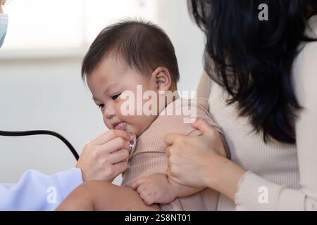 Pediatrician using stethoscope on baby during a checkup with attentive mother Stock Photo